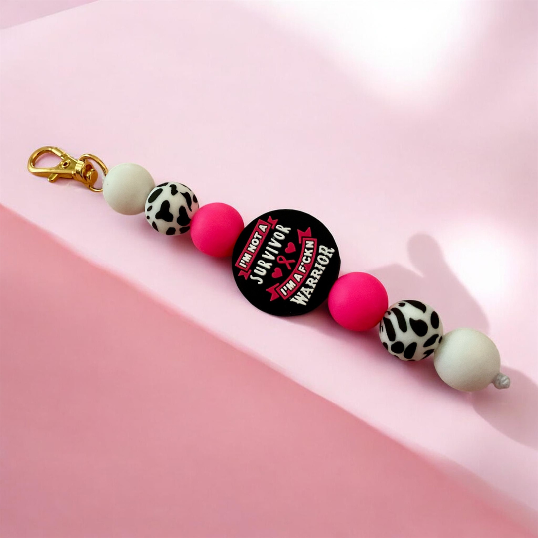 Keychain with colorful beads and a 'Survivor' button on a pink background