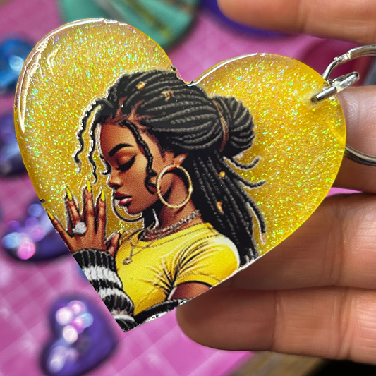 Yellow glitter resin heart keychain featuring praying woman artwork with glossy handmade finish.