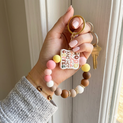 Hand holding a colorful keychain with a key against a neutral background